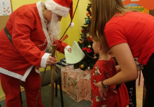 Mikołaj wręcza prezenty dzieciom.