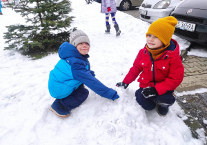Janek i Kajtek tworzą górkę ze śniegu