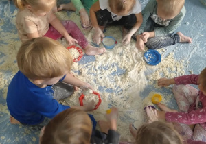 Dzieci zaczynają zabawę w sensorycznym, sztucznym śniegu.